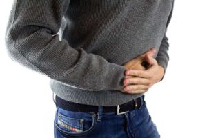 man holding stomach due to pain from crohn's disease