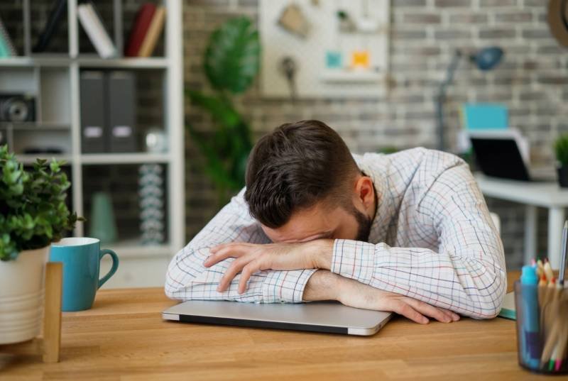 Man rest head on table experiencing Chronic Fatigue